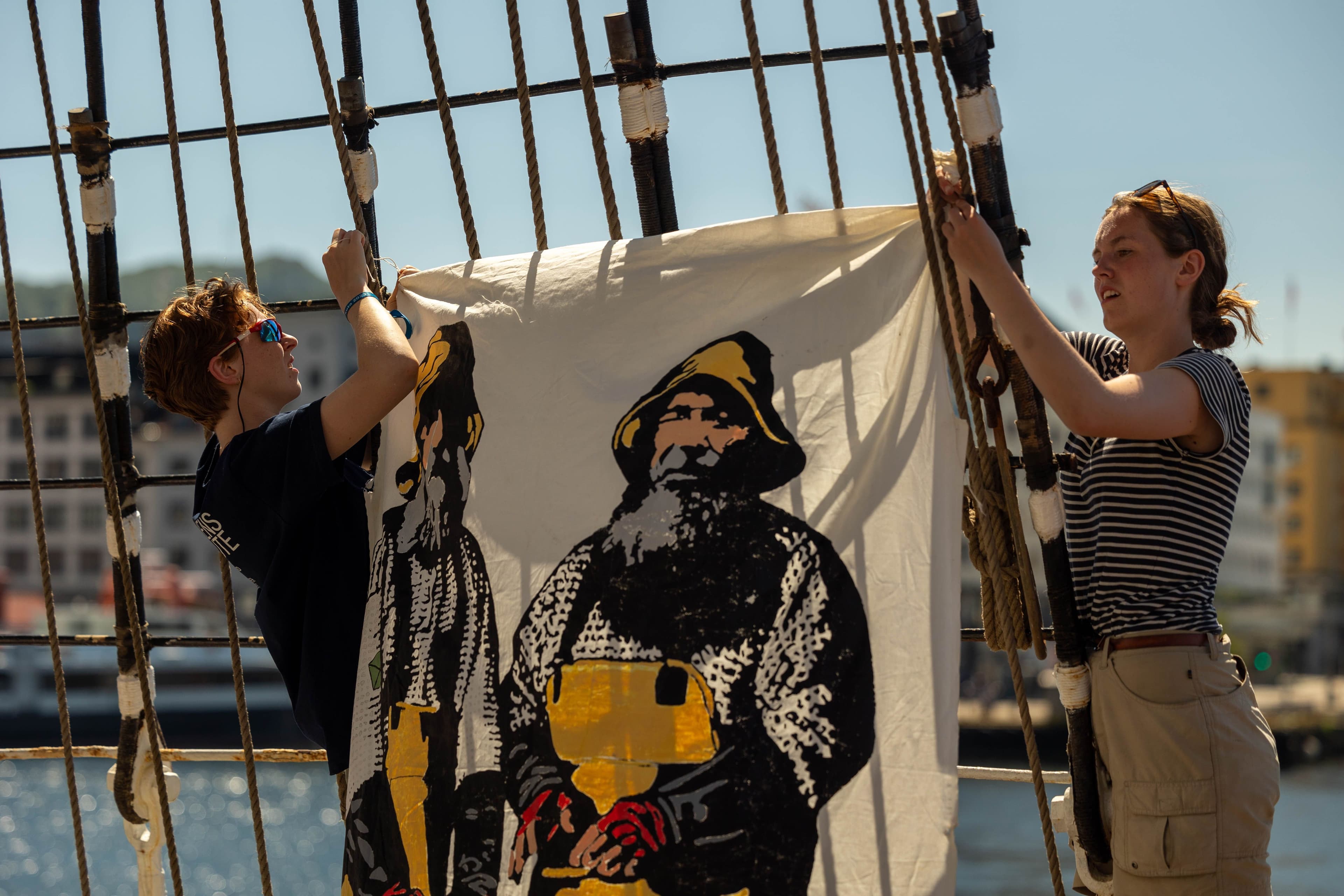 Bilde av ungdommer som henger opp banner på skip