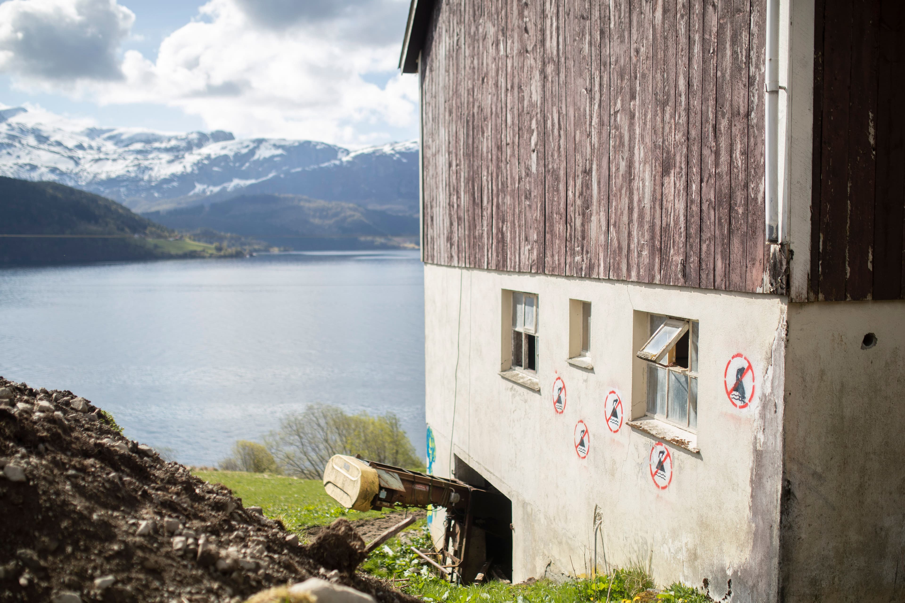 Hus ved Førdefjorden, med "Nei til gruvedumping"-logo spraymalt på ytterveggene
