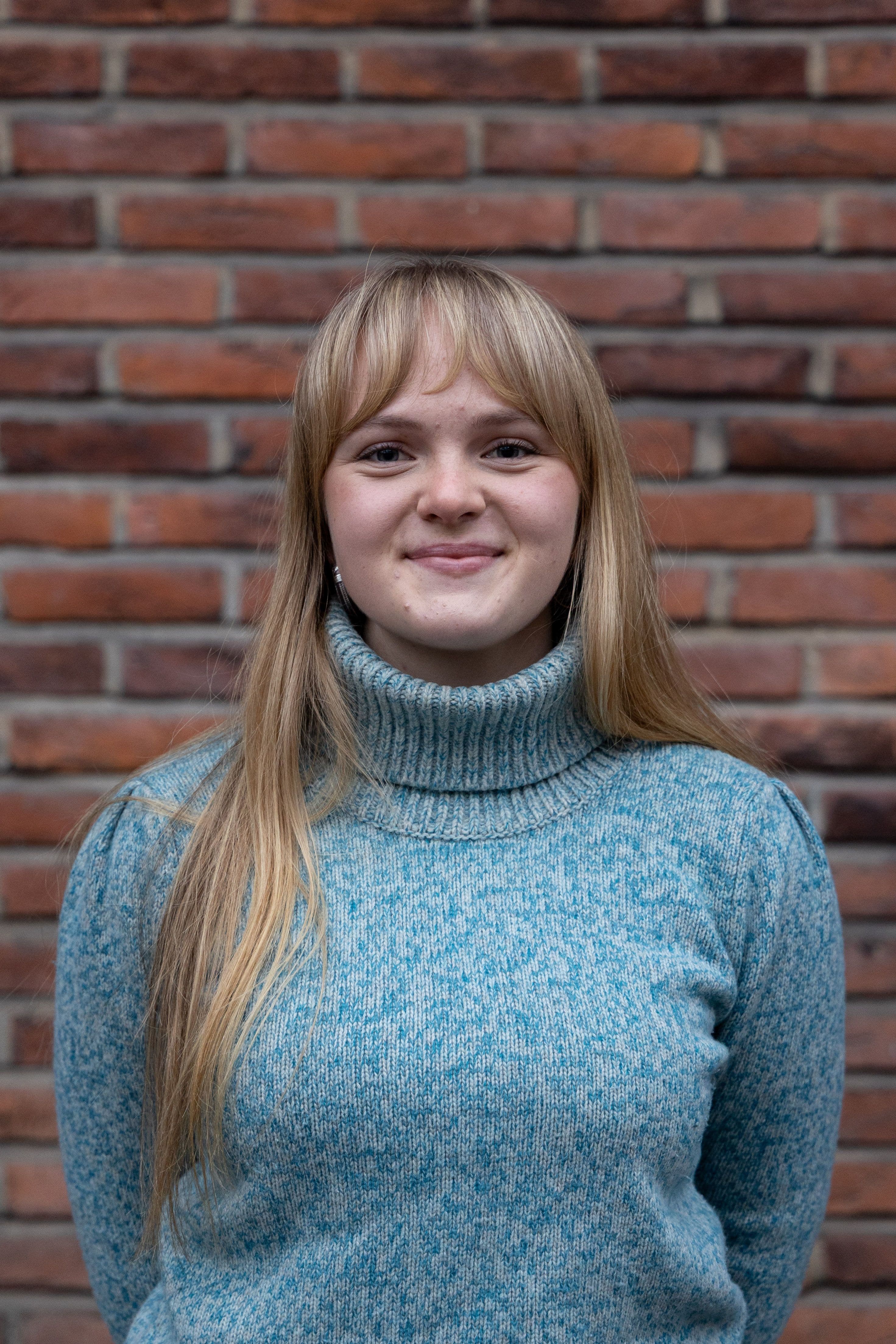 Person smiler foran murvegg