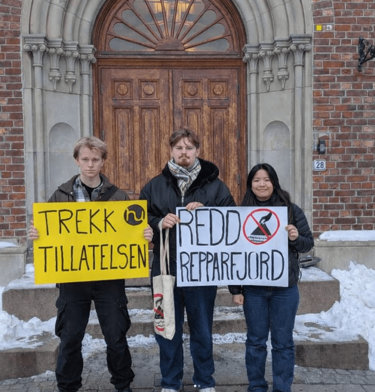 Tre aktivister i Kristiansand med plakater med teksten "Trekk tillatelsen"