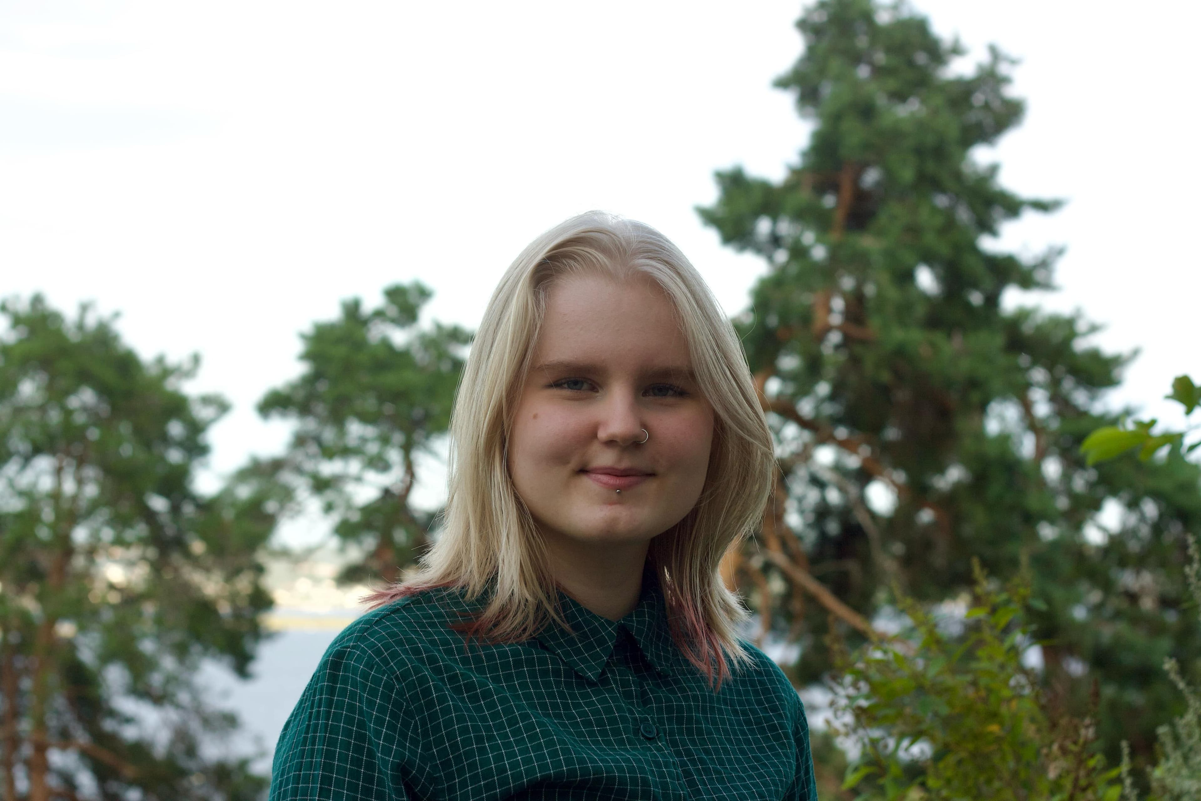 Portrett av Iana - Jente med blondt hår i forgrunnen, skog i bakrunnen