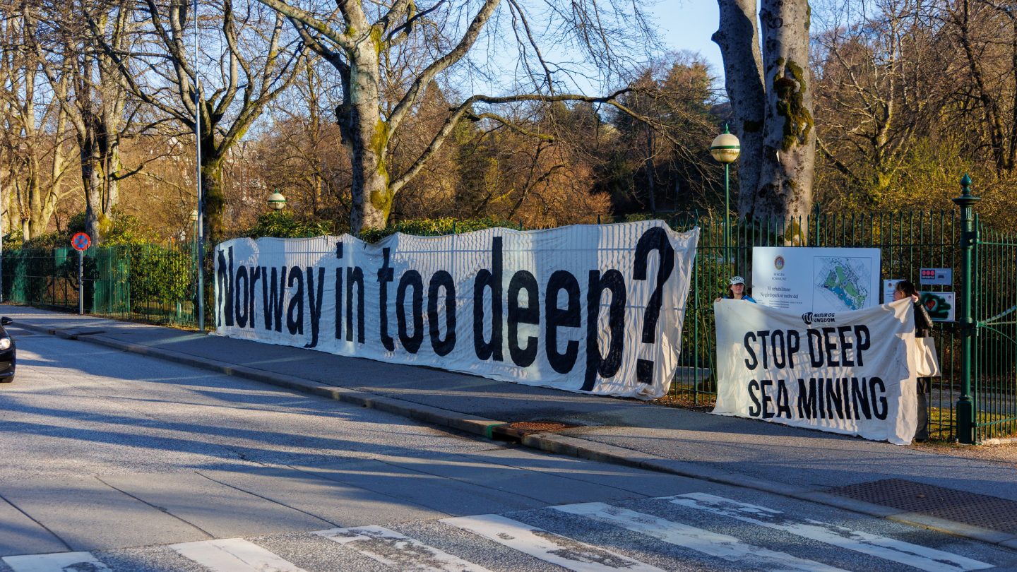 Banner med tekst "Norway in too deep?" henger på gjerde i Bergen