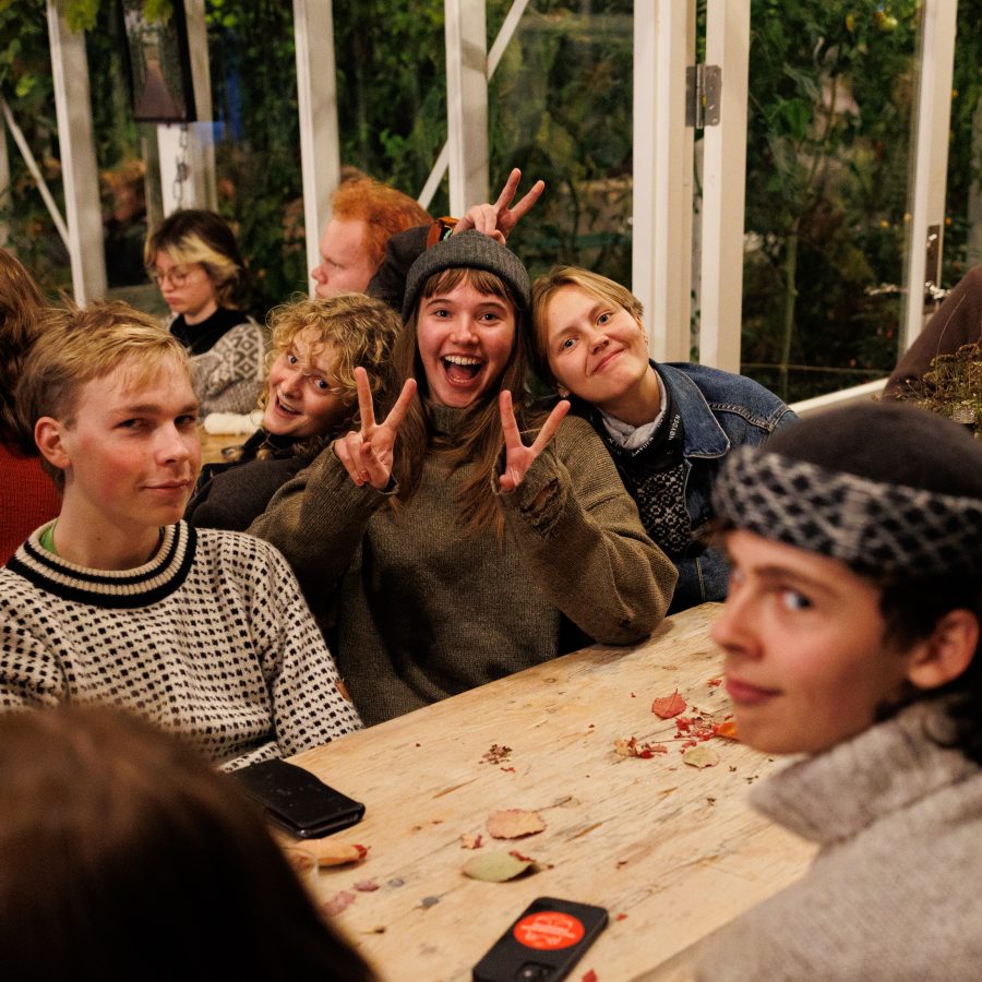 Ungdommer sitter sammen rundt et bord og smiler.